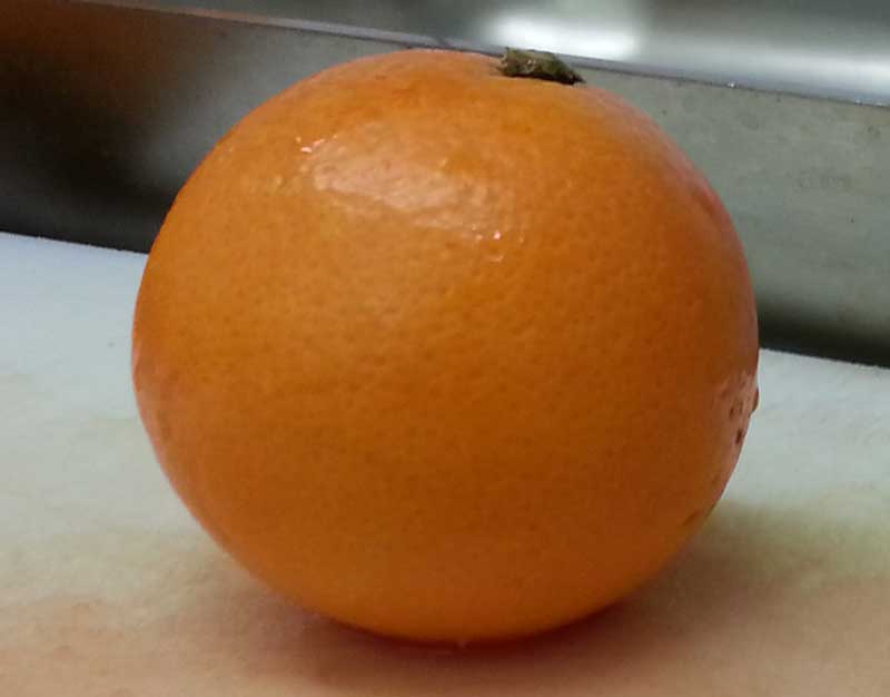 bild. Eine Orange auf dem Schneidebrett